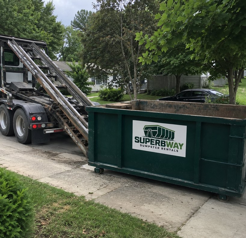 Roll-off truck lowering a Superbway container onto a residential driveway